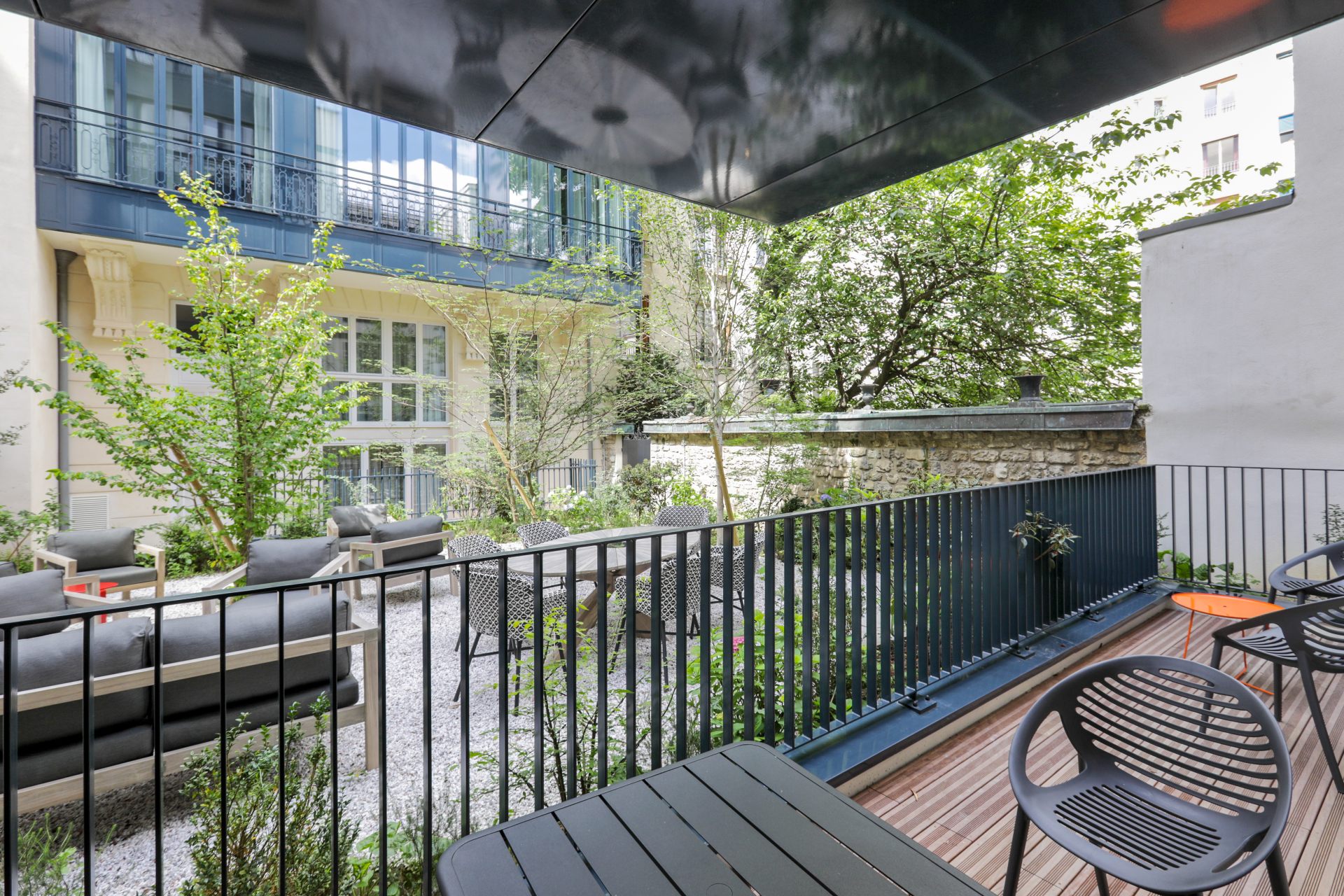 Cour intérieure arborée et paisible du Mode Paris Aparthotel, un espace de détente privé avec mobilier de jardin au cœur du 16ème arrondissement.
