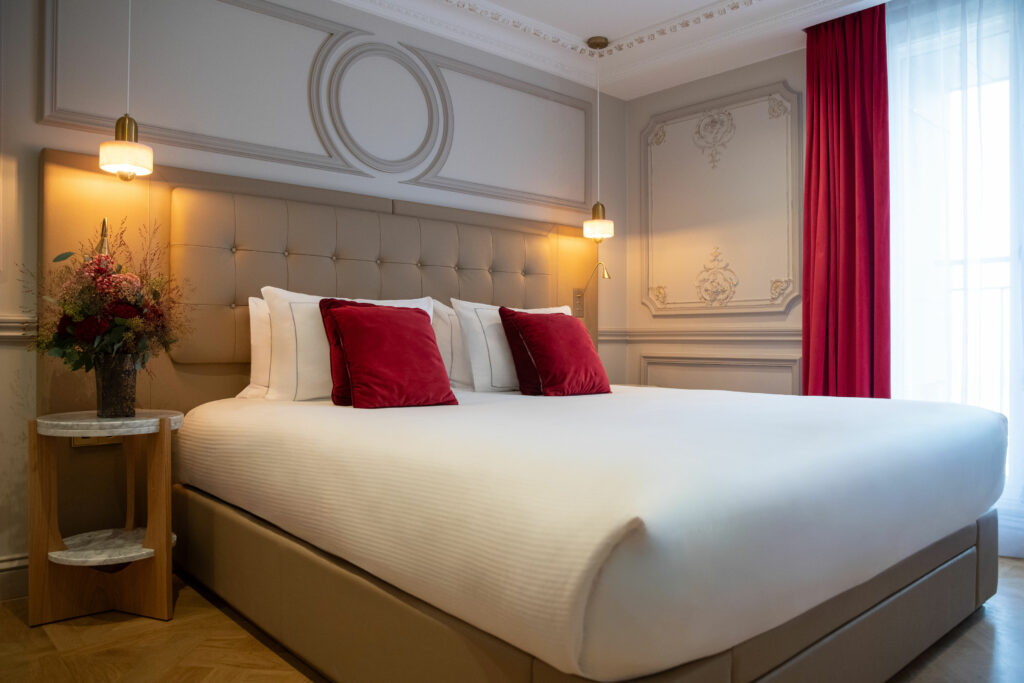 Suite de luxe à Maison Triomphe Paris : coussins en velours bordeaux, tête de lit capitonnée, moulures haussmanniennes et suspensions en albâtre, hôtel-résidence 5 étoiles Paris 16