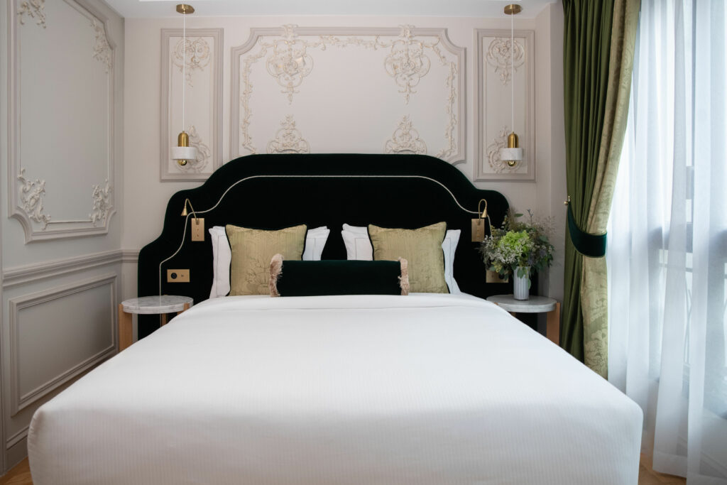 Suite de luxe à Maison Triomphe Paris : tête de lit en velours vert profond, moulures rehaussées d’or et rideaux en damas, hôtel-résidence 5 étoiles Paris 16